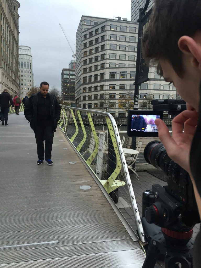 Man walking across a bridge being filmed