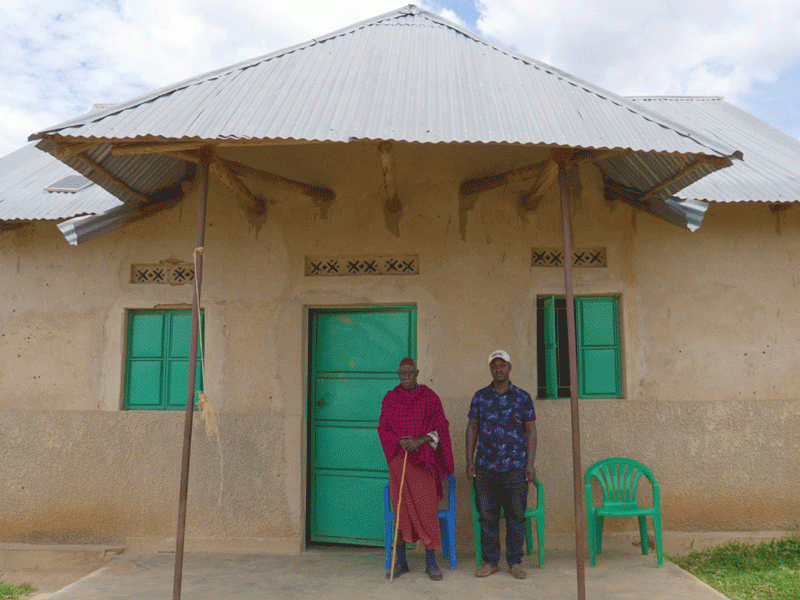 two men outside house in Uganda village